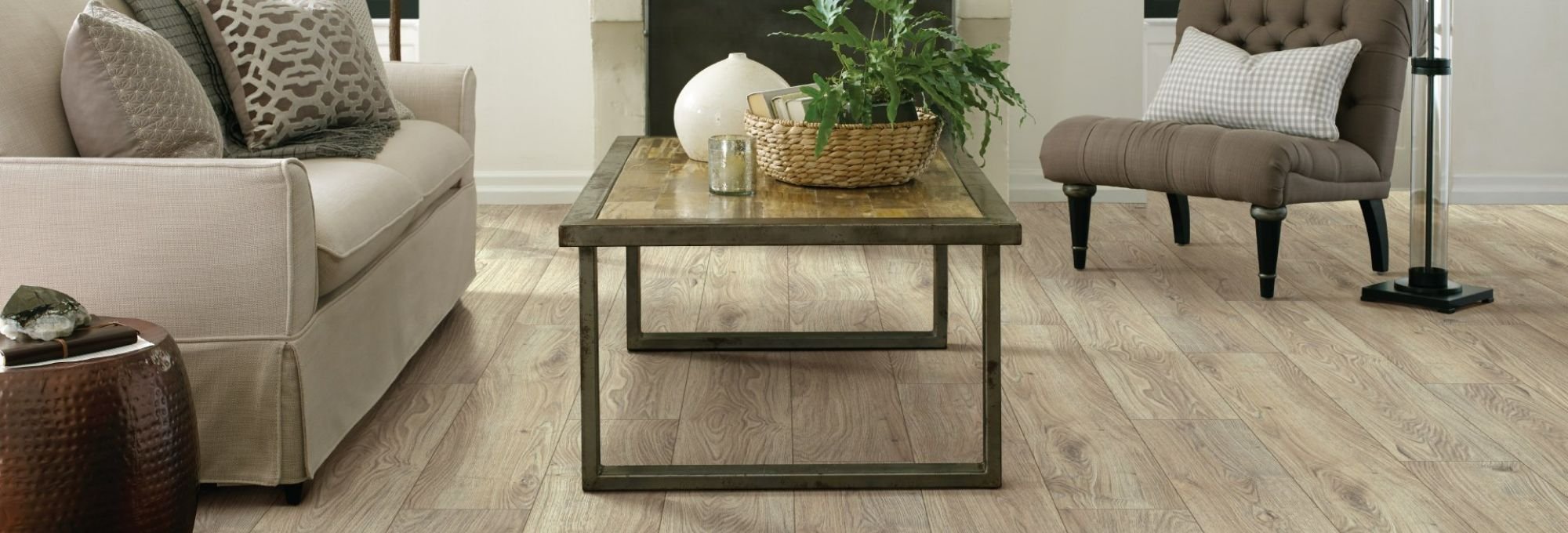 beige couch and brown coffee table in living room with gray laminate floor by Green Carpet Co. - The Flooring Connection in San Antonio, TX